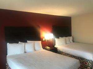 圣安吉洛Red Roof Inn & Suites San Angelo的酒店客房,设有两张床和一盏灯