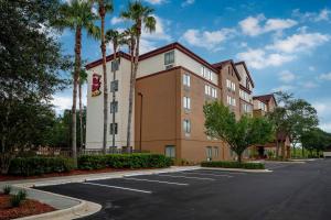 杰克逊维尔Red Roof Inn PLUS+ Jacksonville – Southpoint的停车场内棕榈树的建筑