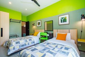 盼武里那普兰泳池别墅的两张床位于带绿色和黄色墙壁的客房
