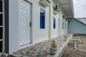 巴东OYO 3266 Alifah Residence Syariah的庭院上有一扇白色的门和两株盆栽植物