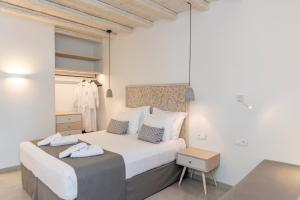 提诺斯Lithos Luxury Suites的卧室配有一张白色的大床和一张桌子
