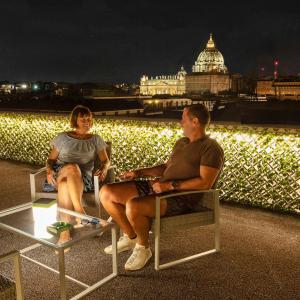 罗马瑞雷斯德伊帕皮酒店的男人和女人在晚上坐在阳台上的椅子上