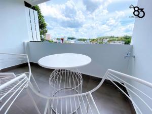 勿洞The 83 Betong GuestHouse的阳台上配有白色的桌椅和窗户