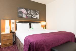 曼彻斯特假日曼切斯特-传媒之城酒店的酒店客房设有一张大床和紫色毯子