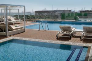 迪拜Holiday Inn & Suites - Dubai Festival City Mall, an IHG Hotel的一个带两把椅子和阴茎的游泳池