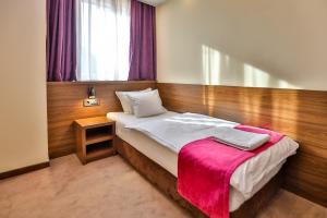 图兹拉金星精品酒店的一间卧室配有一张床铺,床上铺有粉色毯子