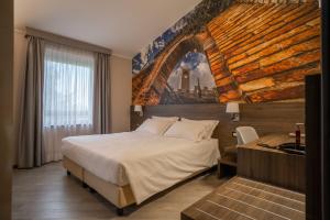 卡斯泰尔韦特罗迪莫德纳古耶罗酒店的卧室配有一张大床,墙上挂有绘画作品