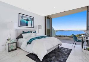 戈斯福德Stylish Penthouse with Views & Jacuzzi的一间卧室设有一张大床和一个大窗户