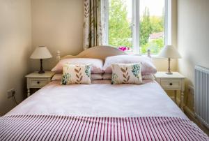 彻奇斯特雷顿Magnolia Cottage的一间卧室配有一张带两盏灯的床和一扇窗户。