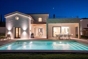萨米Ionian Trilogy Luxury Villas的夜间带游泳池的别墅