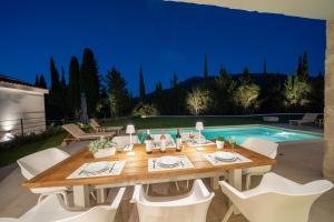 萨米Ionian Trilogy Luxury Villas的一张带白色椅子的餐桌和游泳池