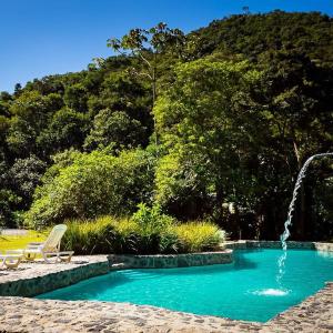 圣弗朗西斯科泽维尔Pousada Vila Santa Barbara的一个带喷泉和椅子的游泳池