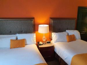 莱昂乐翁圣弗朗西斯科酒店的橙色墙壁的酒店客房内的两张床