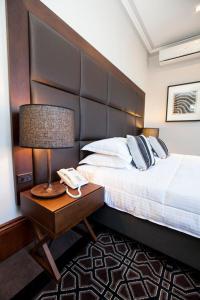 悉尼阿文莫尔公园精品酒店的一间卧室配有一张床和一张带台灯的桌子