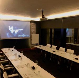 伊兹密尔Emens hotel的一间会议室,配有白色的桌椅和屏幕