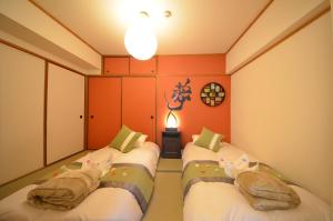 大阪River Side Namba 401的橙色墙壁客房的两张床