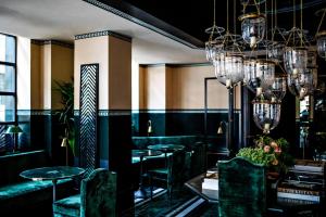 巴黎Monsieur George Hotel & Spa - Champs-Elysées的餐厅设有绿色的桌椅和吊灯