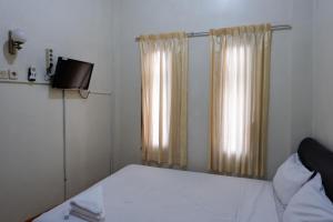 日惹Khresna Guest House Malioboro Mitra RedDoorz的一间小卧室,配有一张床和电视