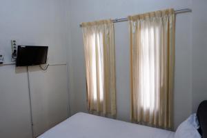 日惹Khresna Guest House Malioboro Mitra RedDoorz的一间卧室配有床和窗帘
