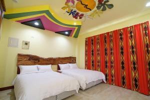 台东马卡巴嗨文创民宿的一间卧室设有两张床和色彩缤纷的天花板