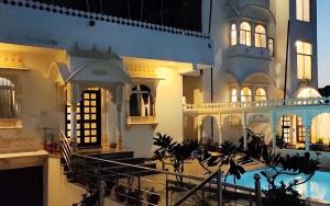 乌代浦Royal Heritage Haveli Udaipur的一座大型建筑,前面设有一个游泳池