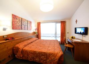 瓦尔迪佐多可乐娜酒店的一间卧室配有一张床、一张书桌和一台电视
