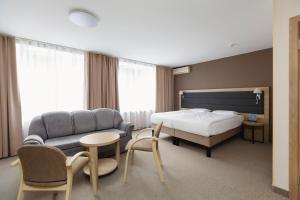 沃罗涅什阿马克斯度假酒店的一间卧室配有一张床、一张沙发和一张桌子