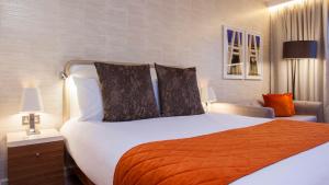 伦敦伦敦国王十字皇冠假日酒店的一间卧室配有一张大白色床和橙色毯子