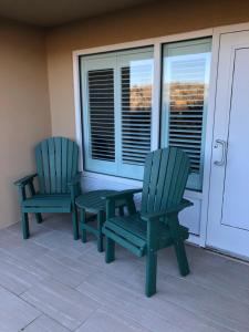 斩魔山河岸百叶窗酒店的门廊上设有两张绿色椅子和一张桌子
