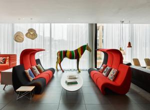 格拉斯哥格拉斯哥世民酒店的客厅配有2把红色椅子和1个马雕像