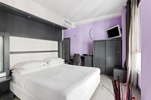 那不勒斯黄金酒店的卧室配有一张白色大床和紫色墙壁
