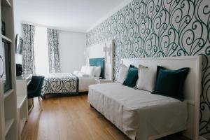 的里雅斯特Hotel Città di Parenzo的一间卧室设有两张床,墙上贴有壁纸。