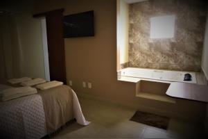 圣若昂-德雷Terra D` Ouro Apart Hotel的浴室设有床、水槽和窗户。