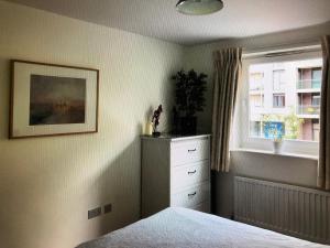 泰晤士河畔金斯顿Kingston Flat的一间卧室配有一张床、一个梳妆台和一扇窗户。