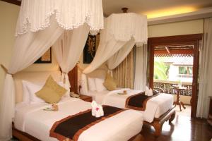 清迈Khum Phaya Resort & Spa Boutique Collection的一间卧室配有两张床、窗帘和窗户