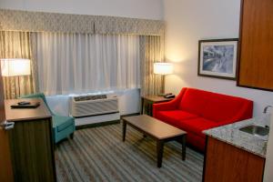 森特尼尔Holiday Inn & Suites Denver Tech Center-Centennial, an IHG Hotel的酒店客房带红色椅子和沙发