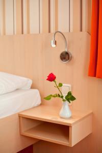 瓦伦慕特兹佩勒酒店的一张桌子上的一个红玫瑰花,放在一个床边的花瓶上