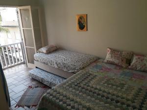 瓜鲁雅Apartamento na enseada 50 metros da praia的一间带两张单人床的卧室和一个阳台