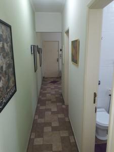 瓜鲁雅Apartamento na enseada 50 metros da praia的走廊上设有卫生间和走廊的浴室