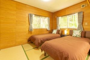 石垣岛Villa Itona的配有木墙和窗户的客房内的两张床