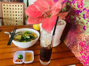 芹苴Mekong Rose Hotel的坐在一碗食物旁边的桌子上喝一杯