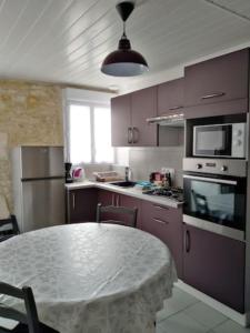 拉康提内勒La Flottille, La Cotinière的厨房配有紫色橱柜和桌子