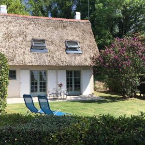 厄镇Le Lodge des Prés的两把蓝色椅子坐在房子前面的草上
