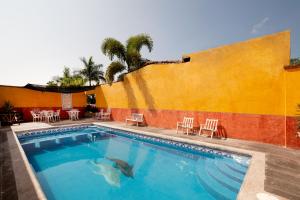 里奥韦尔德Hotel Villas De San Miguel Media Luna的一座带椅子的建筑前的游泳池