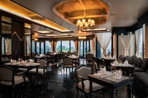 河内La Sinfonía del Rey Hotel & Spa的一间带桌椅和吊灯的餐厅