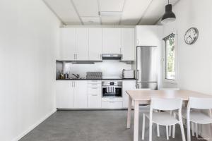 林雪平First Camp Glyttinge-Linköping的厨房配有木桌和白色橱柜。