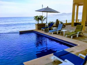 巴拉德纳维达巴格凡特酒店 的一座带椅子和遮阳伞的游泳池,毗邻大海