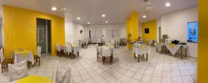 纳韦甘蒂斯Pousada Cores的餐厅设有白色的桌椅和黄色的墙壁