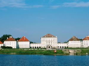 嘉兴贝慕尼黑慕尼黑加尔兴宜必思酒店的一座白色的大建筑,有红色的屋顶,靠近水体