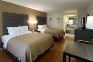 布兰森Quality Inn Branson - Hwy 76 Central的酒店客房设有两张床和一张桌子。